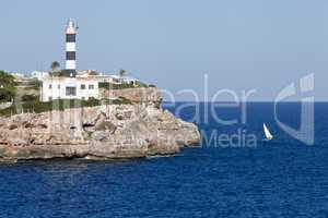 white lighthouse on rocks in the sea ocean water sky blue