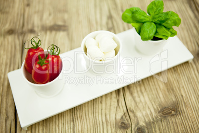 tasty tomatoes mazarella and basil on plate on table