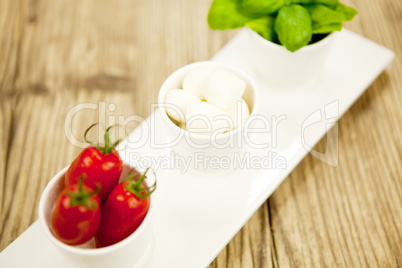 tasty tomatoes mazarella and basil on plate on table