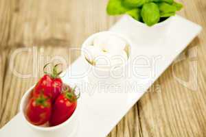 tasty tomatoes mazarella and basil on plate on table