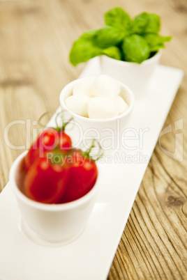 tasty tomatoes mazarella and basil on plate on table