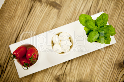 tasty tomatoes mazarella and basil on plate on table