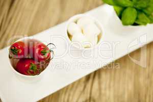 tasty tomatoes mazarella and basil on plate on table