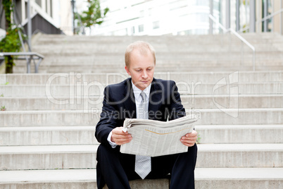 young business man is reading newspaper outdoor