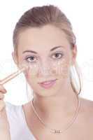 young beautiful woman applying concealer on face