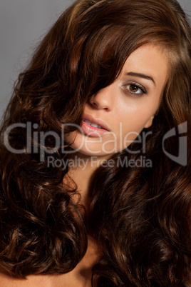 young woman portrait with shiny healthy brown curly hair