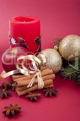 christmas decoration red apple, cinnamon, anise and tree on red background