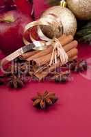 christmas decoration red apple, cinnamon, anise and tree on red background