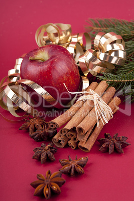 christmas decoration red apple, cinnamon, anise and tree on red background