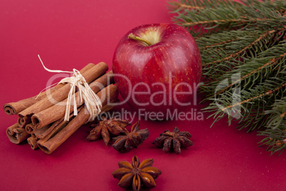 christmas decoration red apple, cinnamon, anise and tree on red background