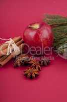 christmas decoration red apple, cinnamon, anise and tree on red background