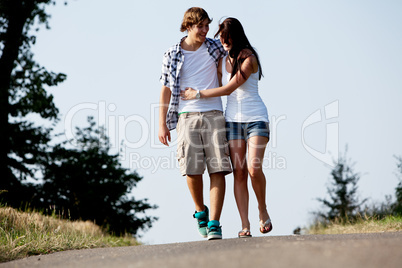 young woman and man is walking on a road in summer outdoor