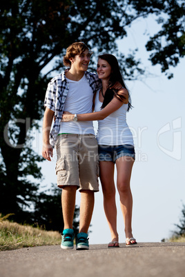 young woman and man is walking on a road in summer outdoor