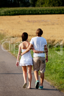 young woman and man is walking on a road in summer outdoor