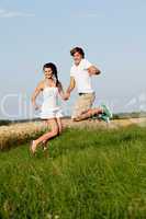 young happy couple jumping outside in summer