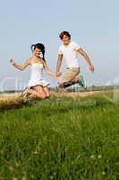 young happy couple jumping outside in summer