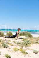 man doing pilates exercises on beach in summer