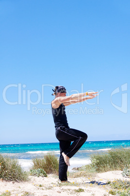man doing pilates exercises on beach in summer
