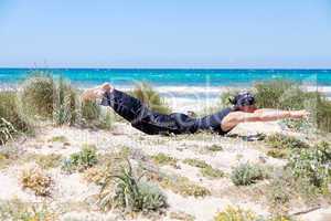 man doing pilates exercises on beach in summer