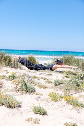 man doing pilates exercises on beach in summer man doing pilates exercises on beach in summer