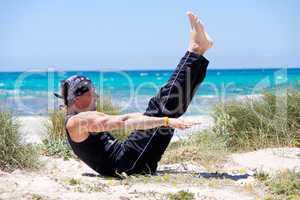 man doing pilates exercises on beach in summer