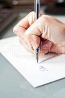 womans hand is writing a letter with a pen