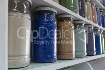 Shelving with glass jars of colorful pigments