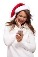 Pretty woman in a Santa hat reading an sms