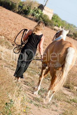young woman walking a road with horse