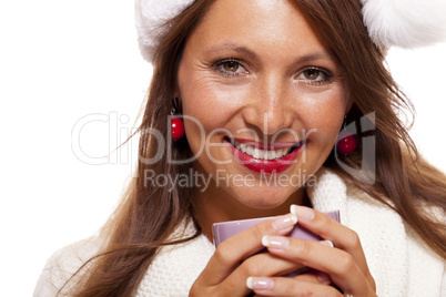 Cold young woman in a Santa hat sipping coffee tea