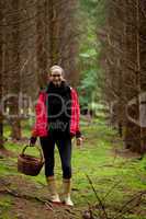 young woman collecting mushrooms in forest