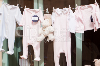 baby clothing and teddy bear in window