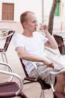 young man sitting outdoor in a cafe in summer