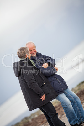 mature happy couple walking on beach in autumn