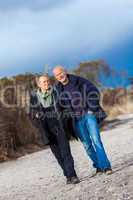 mature senior couple walking on the beach autumn winter