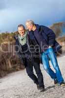 mature senior couple walking on the beach autumn winter