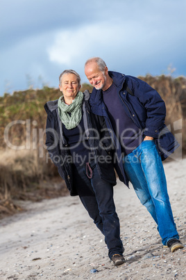 happy elderly senior couple walking on beach