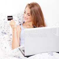 girl sitting in bed and shopping online with credit card