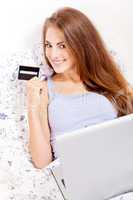 girl sitting in bed and shopping online with credit card