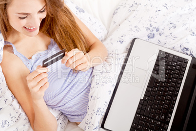 girl sitting in bed and shopping online with credit card