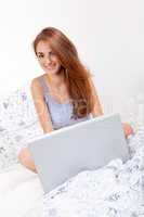 smiling woman sitting on bed with notebook