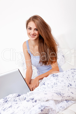 smiling woman sitting on bed with notebook