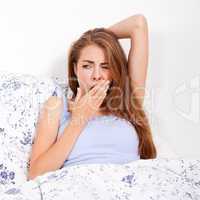 young attractive woman lying in bed yawing portrait tired