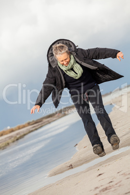 Happy senior woman frolicking on the beach