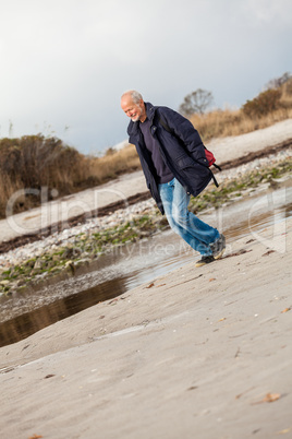 Elderly energetic man running along a beach