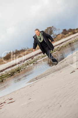 Happy senior woman frolicking on the beach