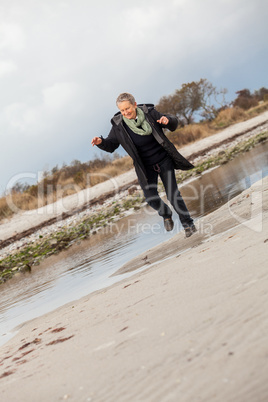 Happy senior woman frolicking on the beach