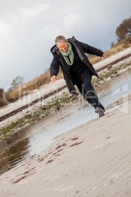 Happy senior woman frolicking on the beach