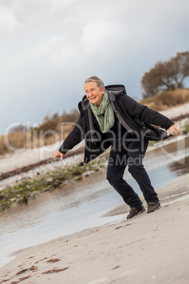 Happy senior woman frolicking on the beach
