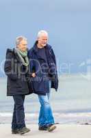 happy elderly senior couple walking on beach